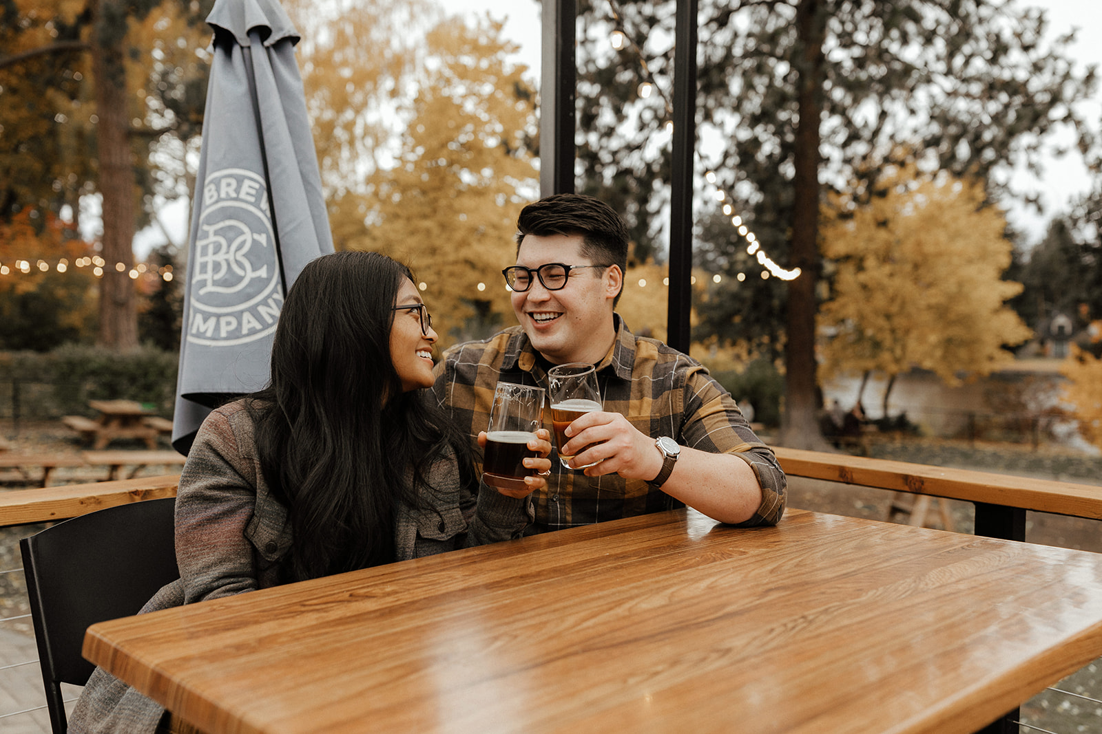 couple holding beer and cheers-ing at a table at Bend Brewing Co.