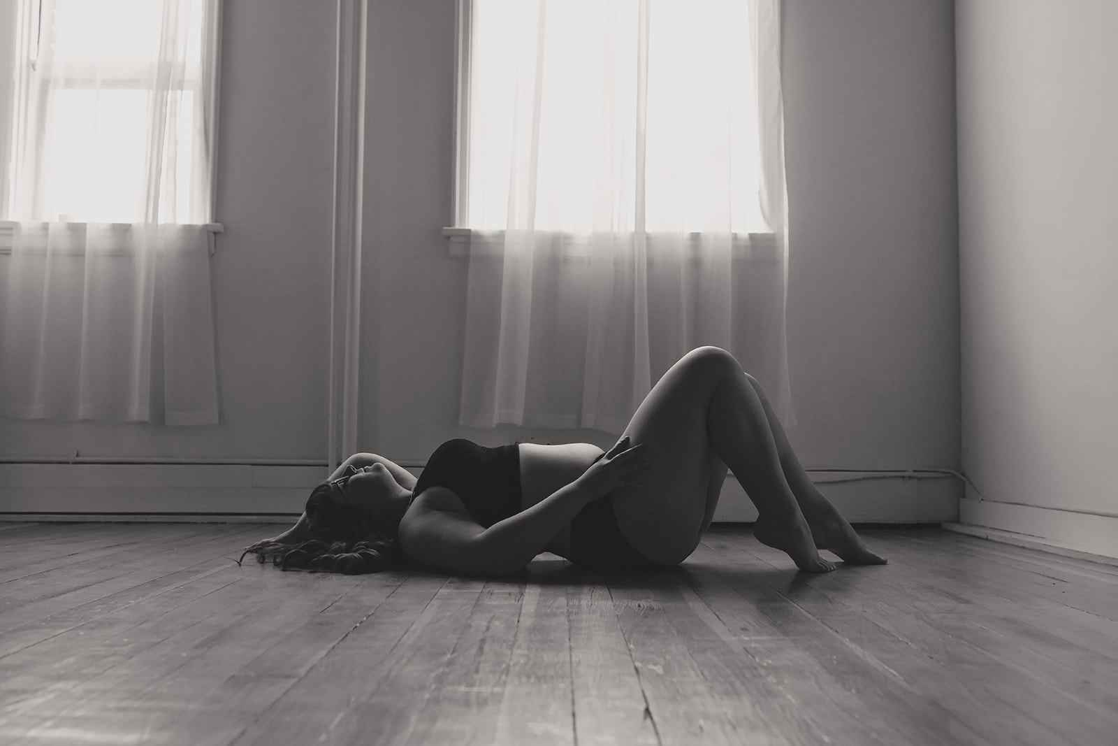 A woman wearing bra and panty set laying on the floor during her boudoir photo session