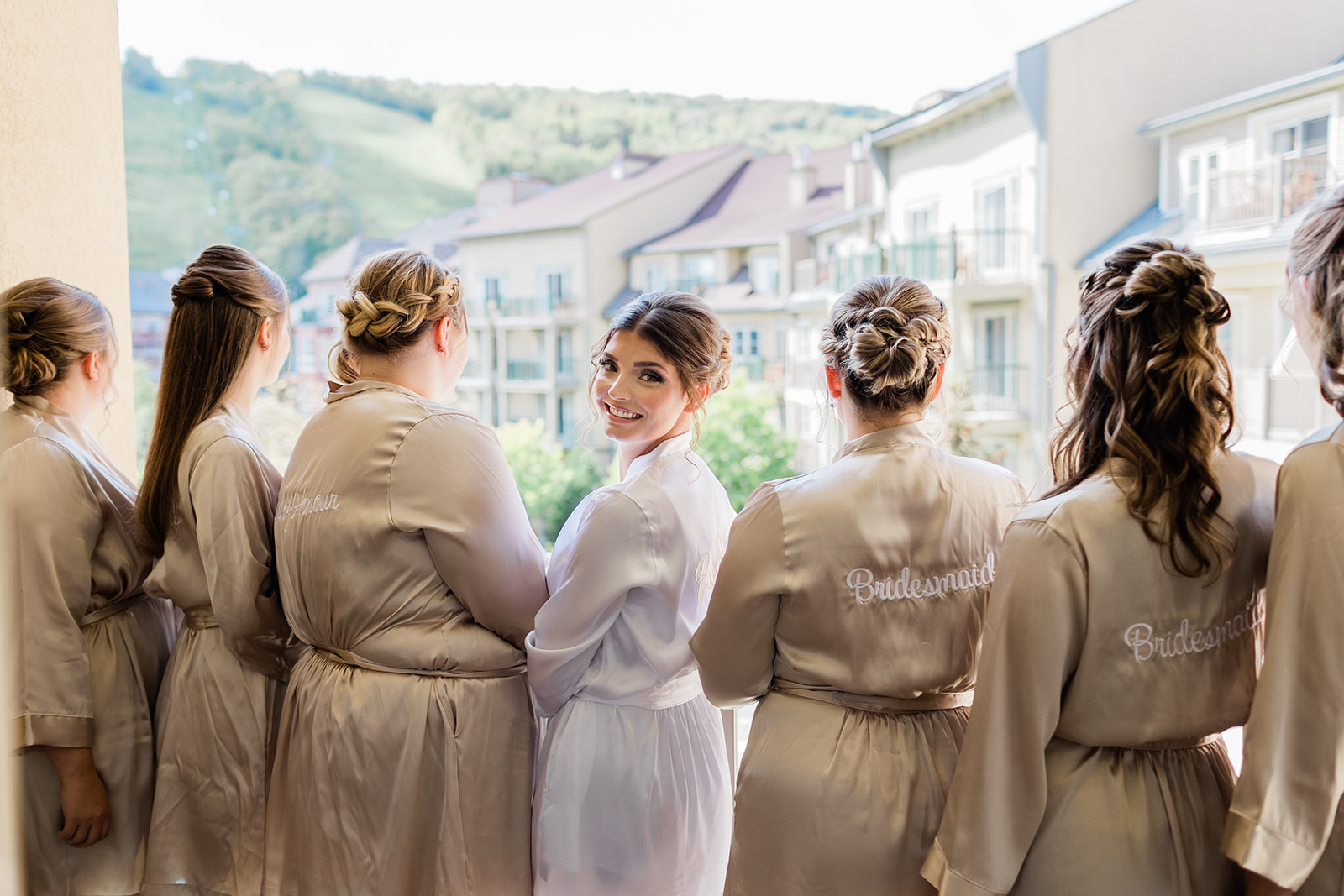 bride and bridesmaids standing on balcony looking out