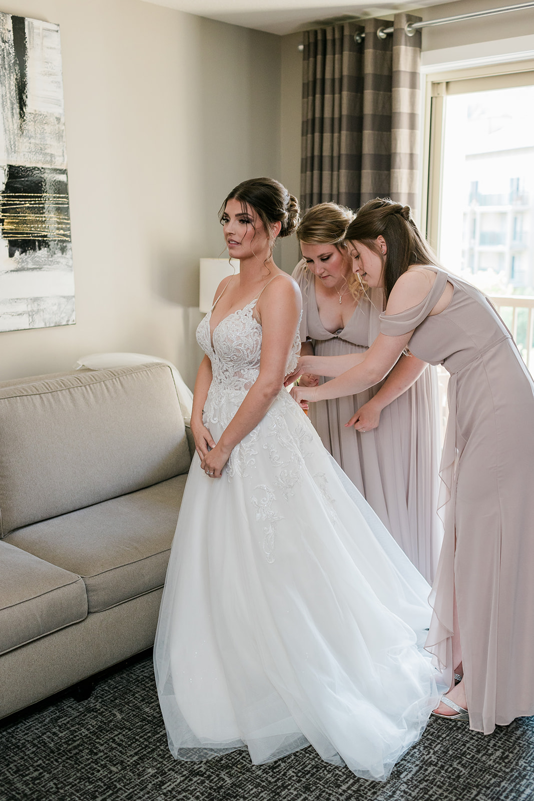 bride in dress getting zipped up by bridesmaids