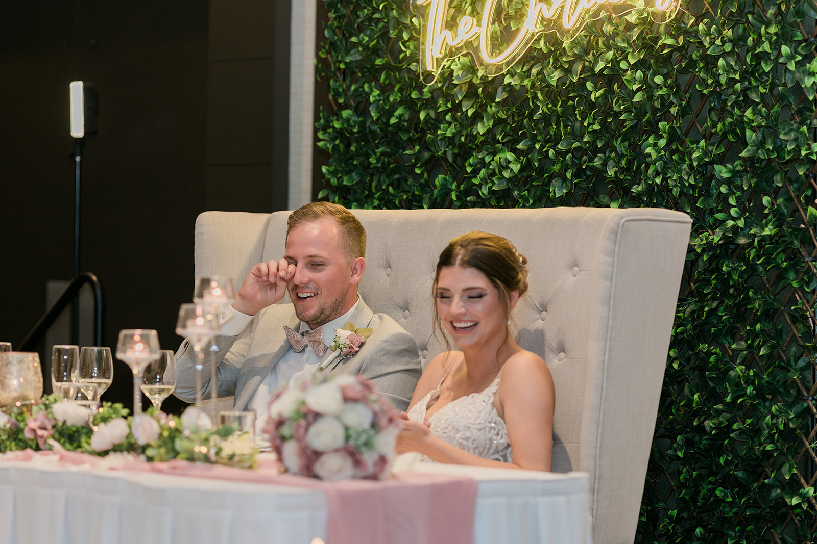 bride and groom laughing at their head table during wedding reception