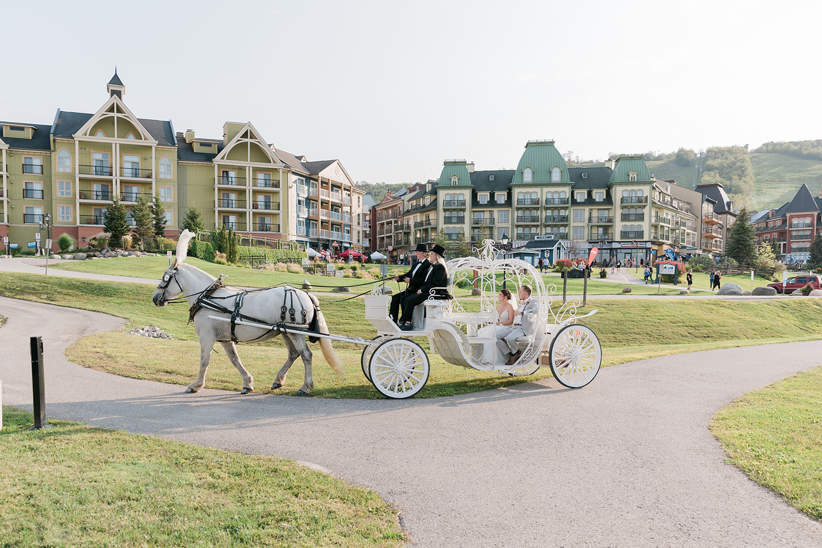 bride and groom riding in the carriage with Blue Mountain Village in the background