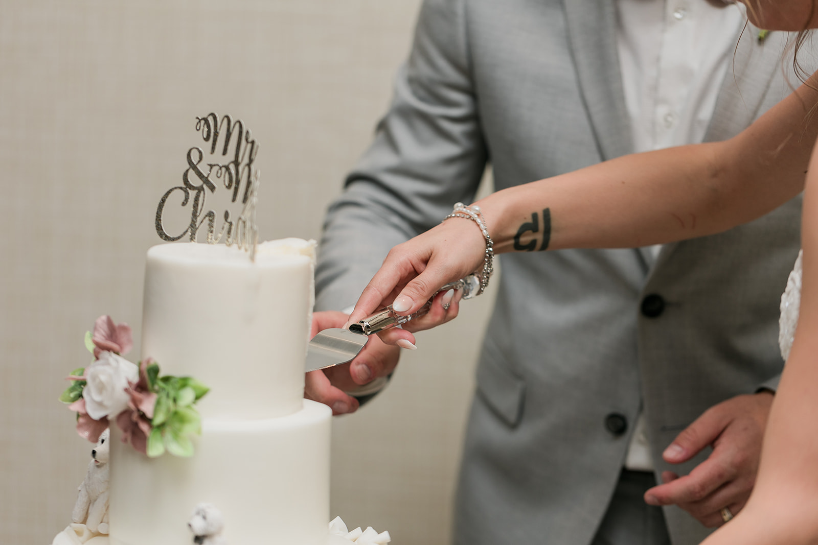close up of couple cutting wedding cake holding knife