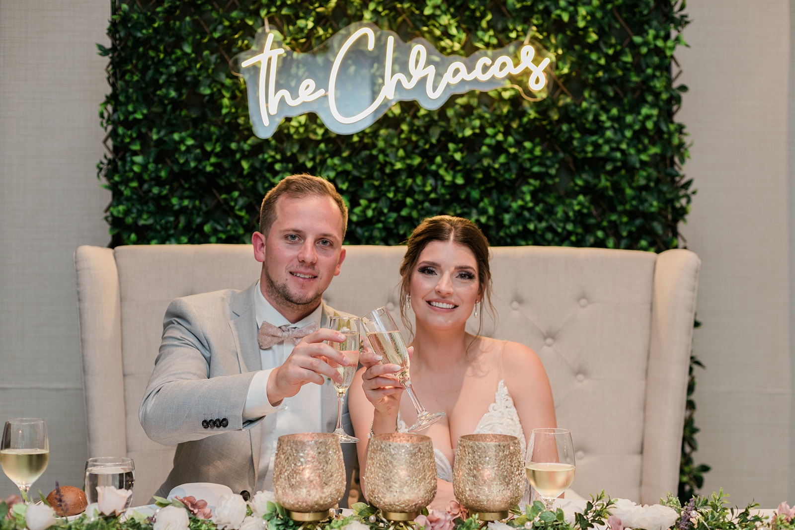 couple toasting champagne while sitting at thier head table