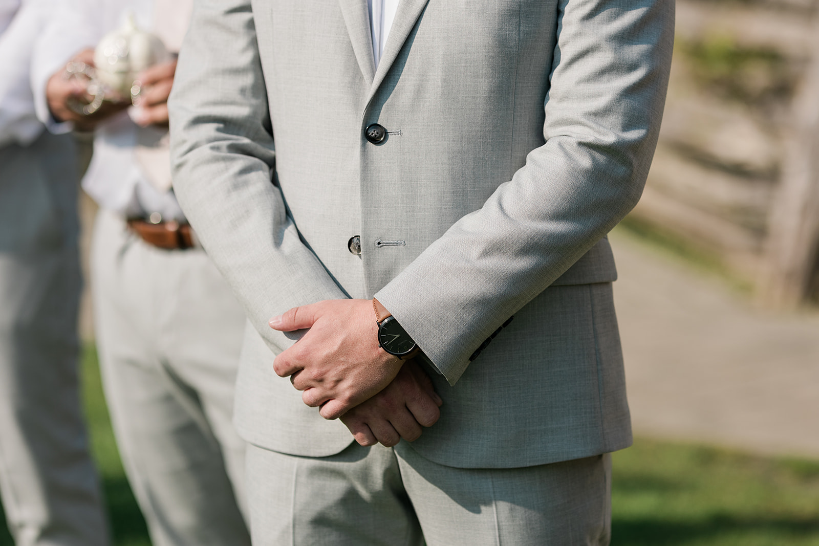 groom with hands crossed waiting at ceremony