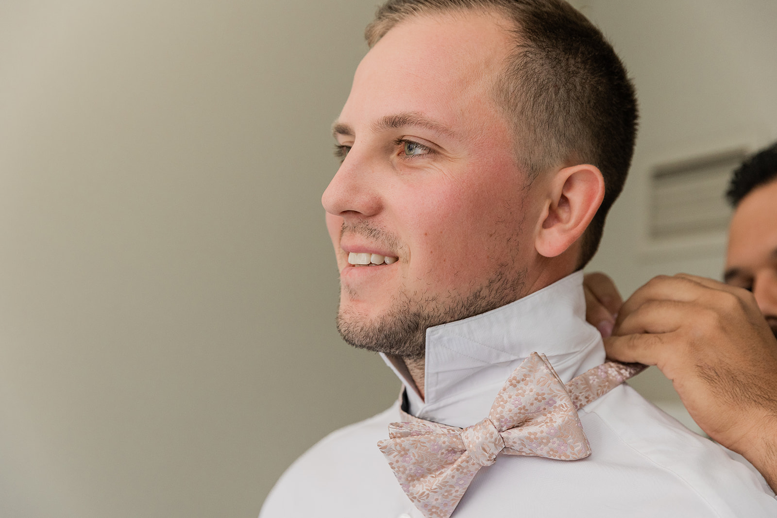 groomsman putting on the grooms tie
