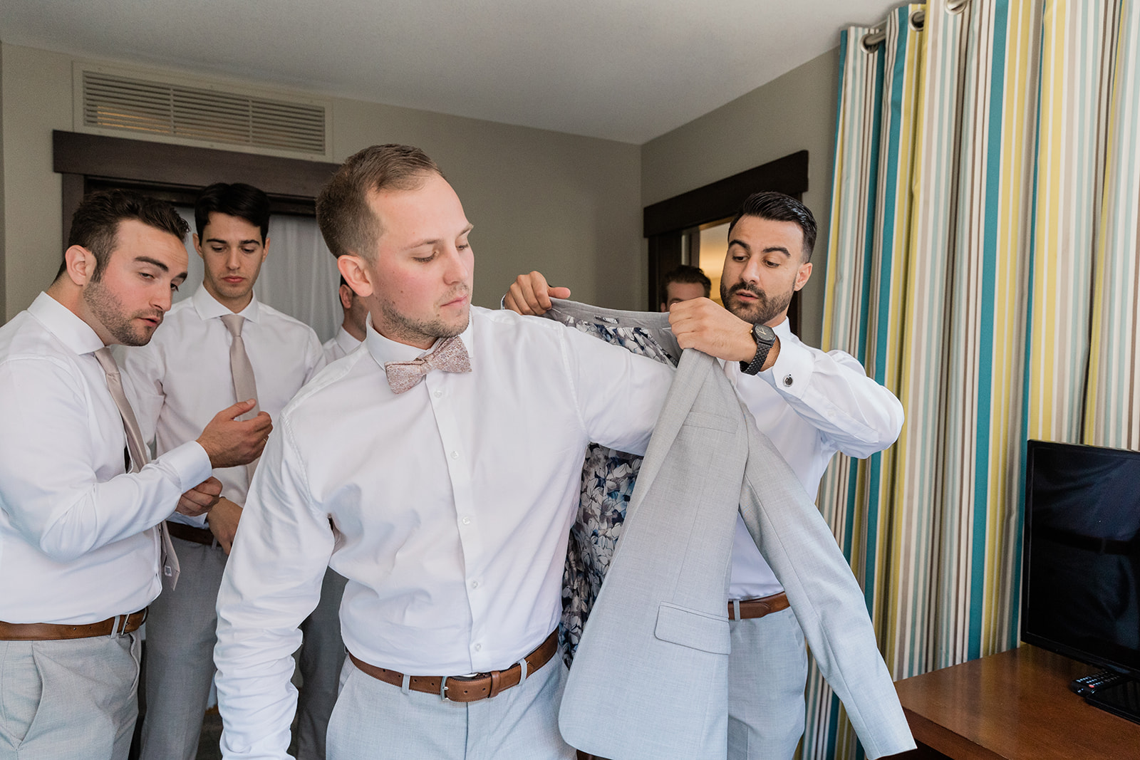 groomsmen putting the jacket on the groom