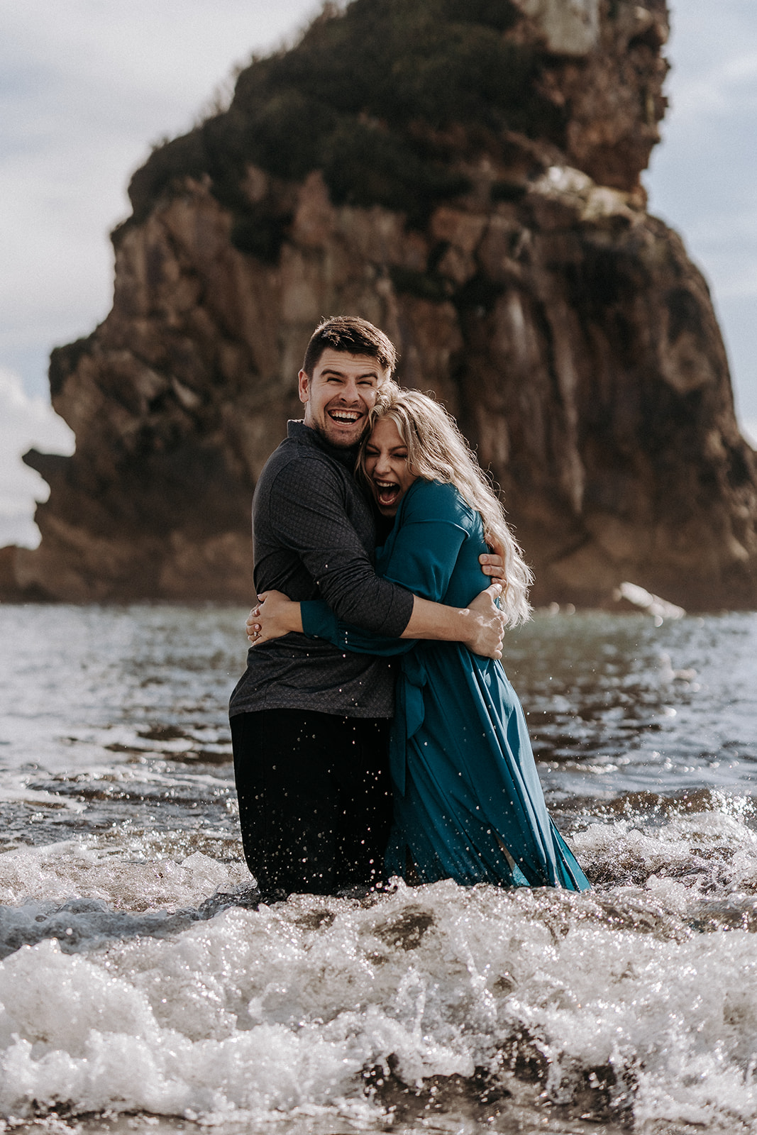 An elopement couple standing in the water in Southern Oregon screaming as a wave hits them.