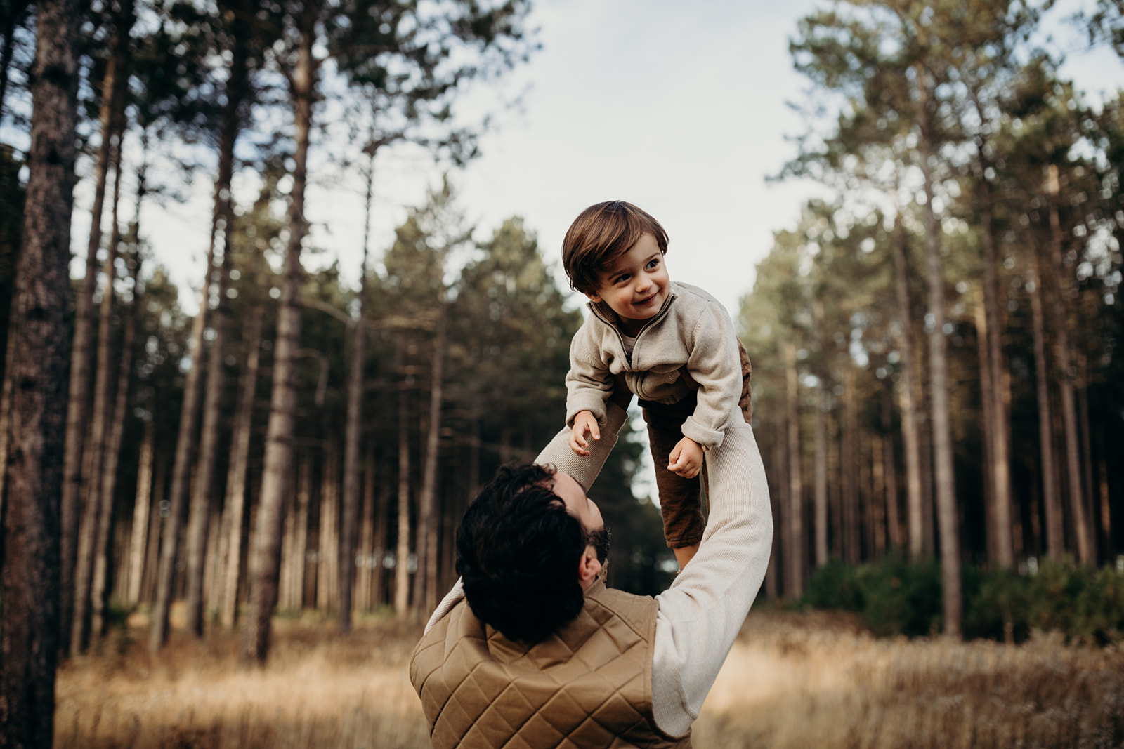 Dad holds smiling baby in the air during Fall family photoshoot 