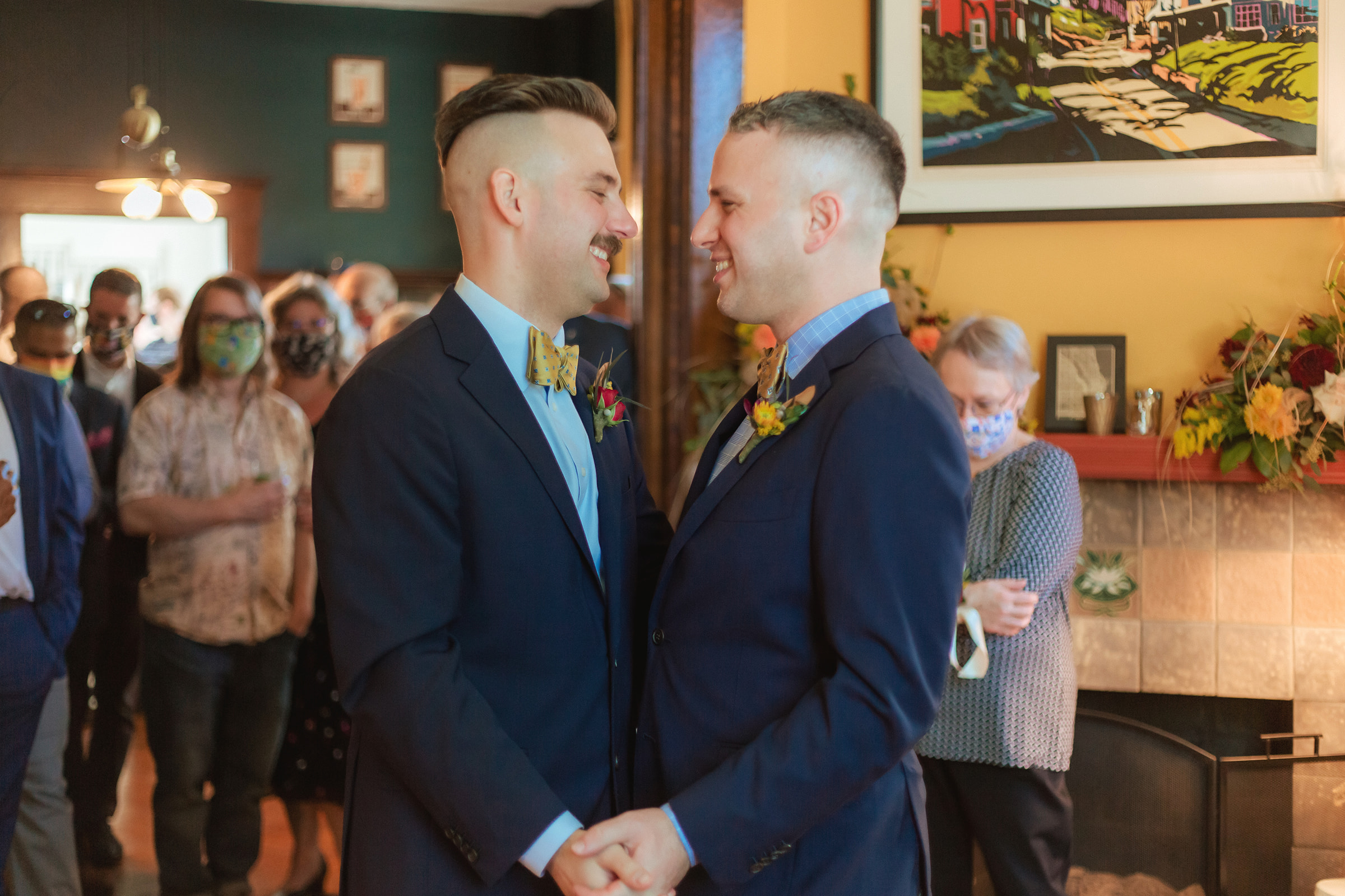 two grooms smiling at each other holding hands