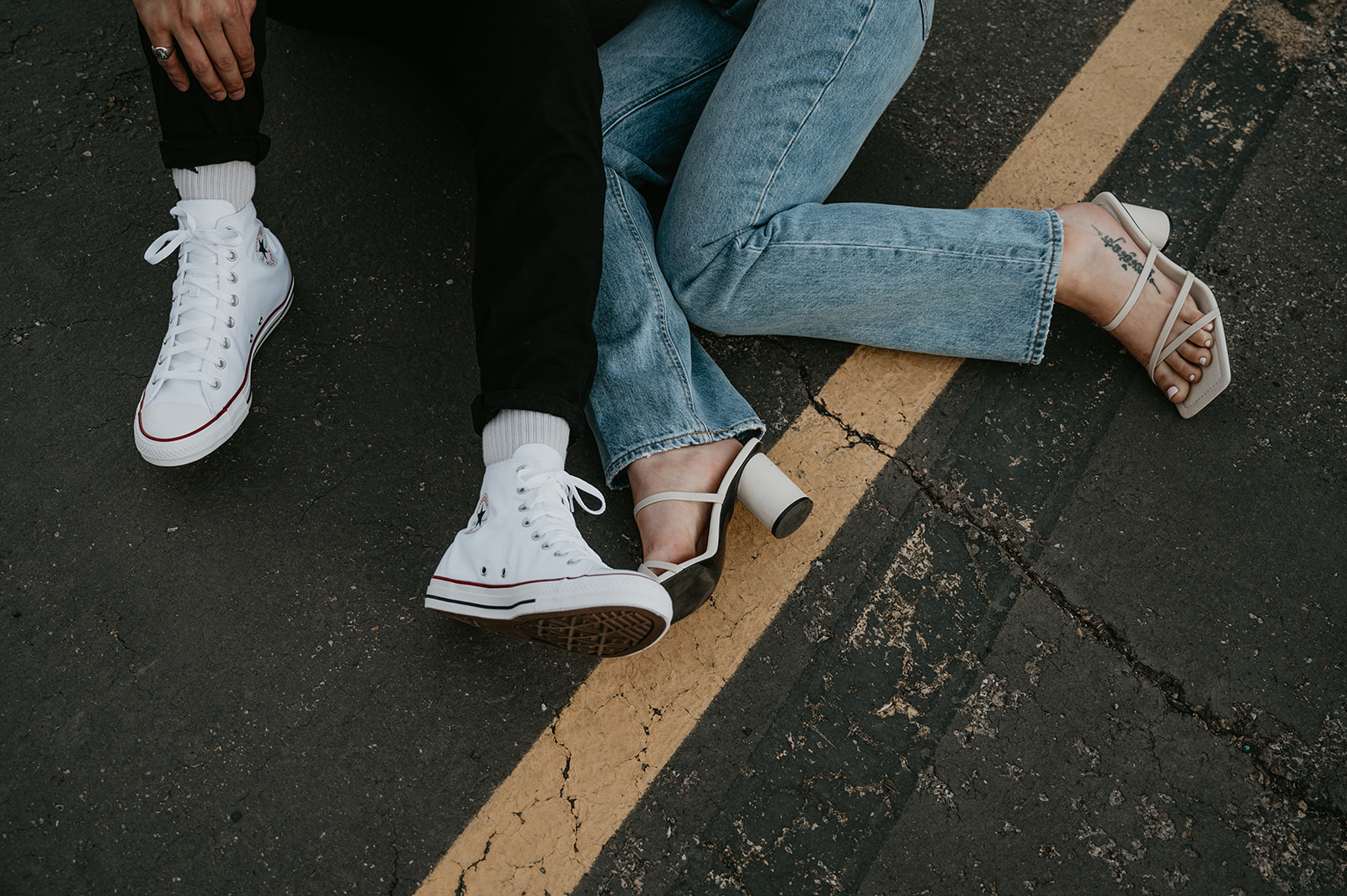 close up photo of a couples feet with heels and converse at a rooftop parking garage in Calgary Alberta