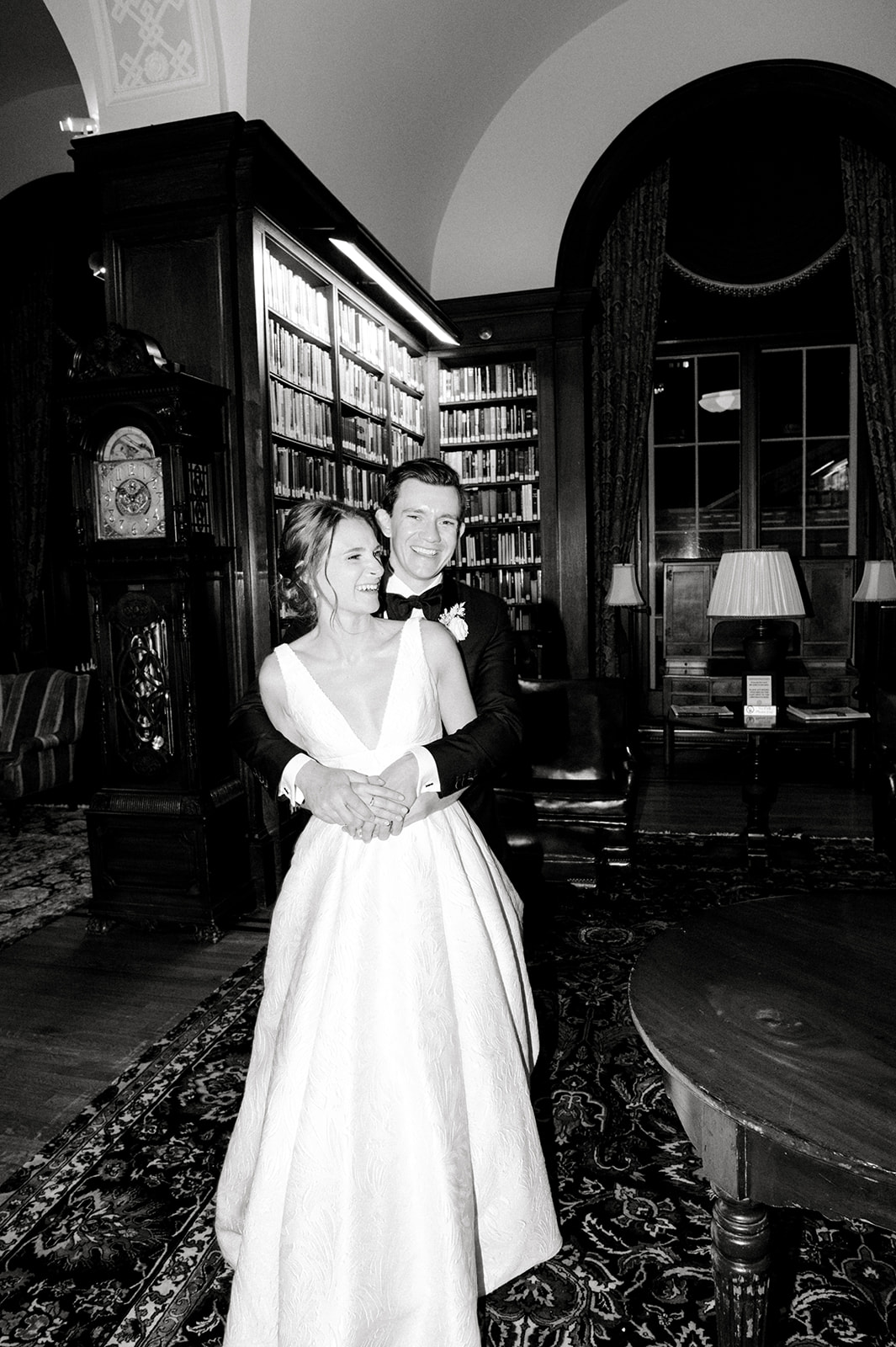 black and white photo of bride and groom excitedly embracing in library of Union League of Philadelphia wedding