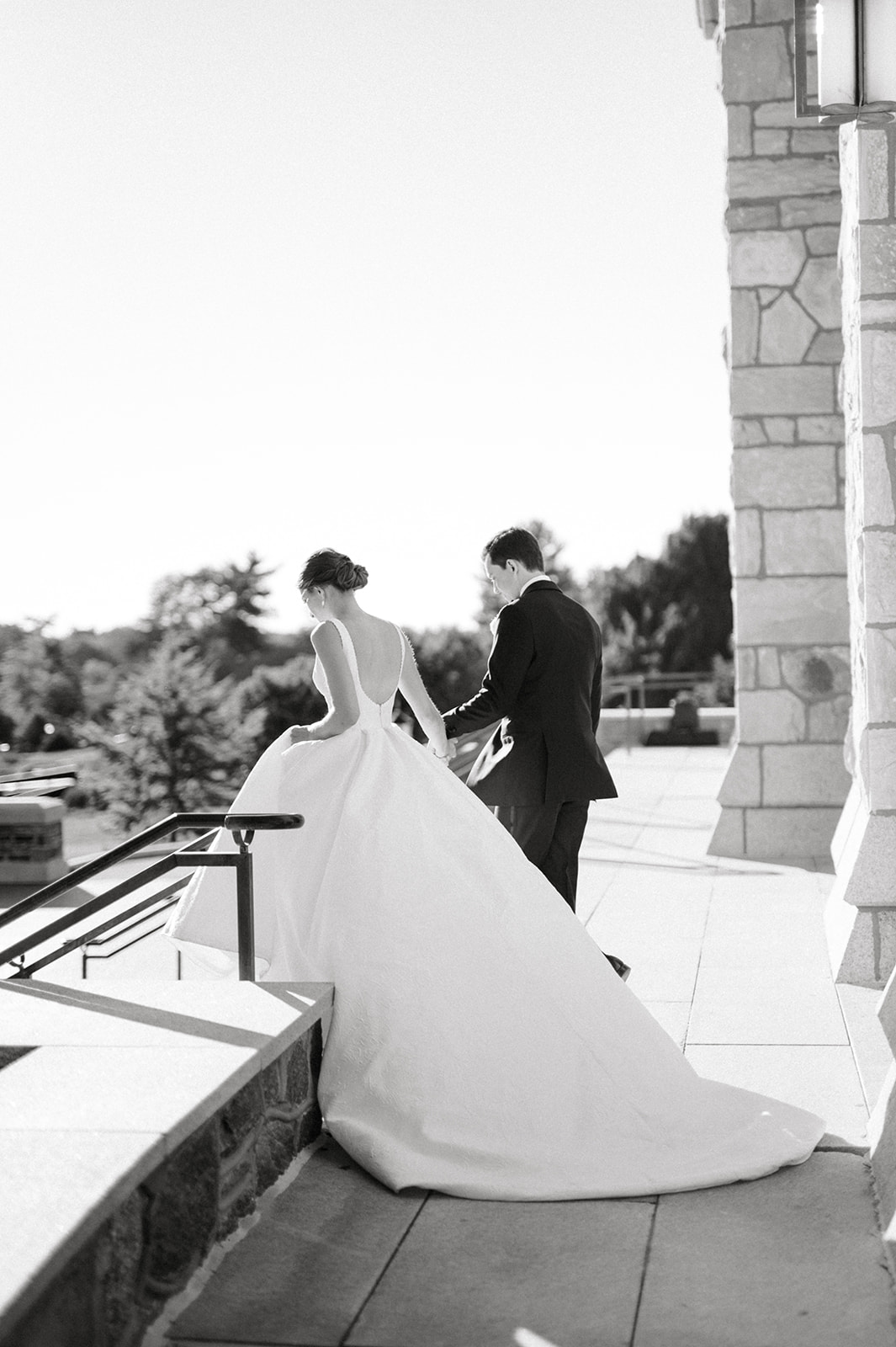 black and white photo of bride and groom walking away at Villanova with large dramatic ballgown