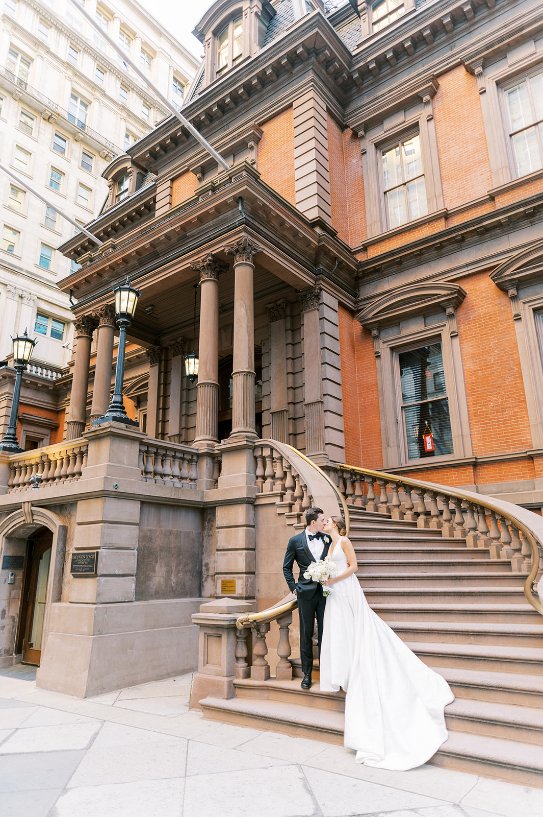 bride and groom pose outside on the steps of the union league of Philadelphia