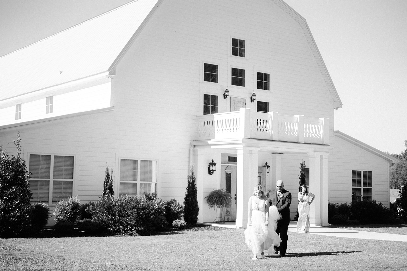 The bride and her father walk out of the barn at Harvest Hollow to see her groom for the first time