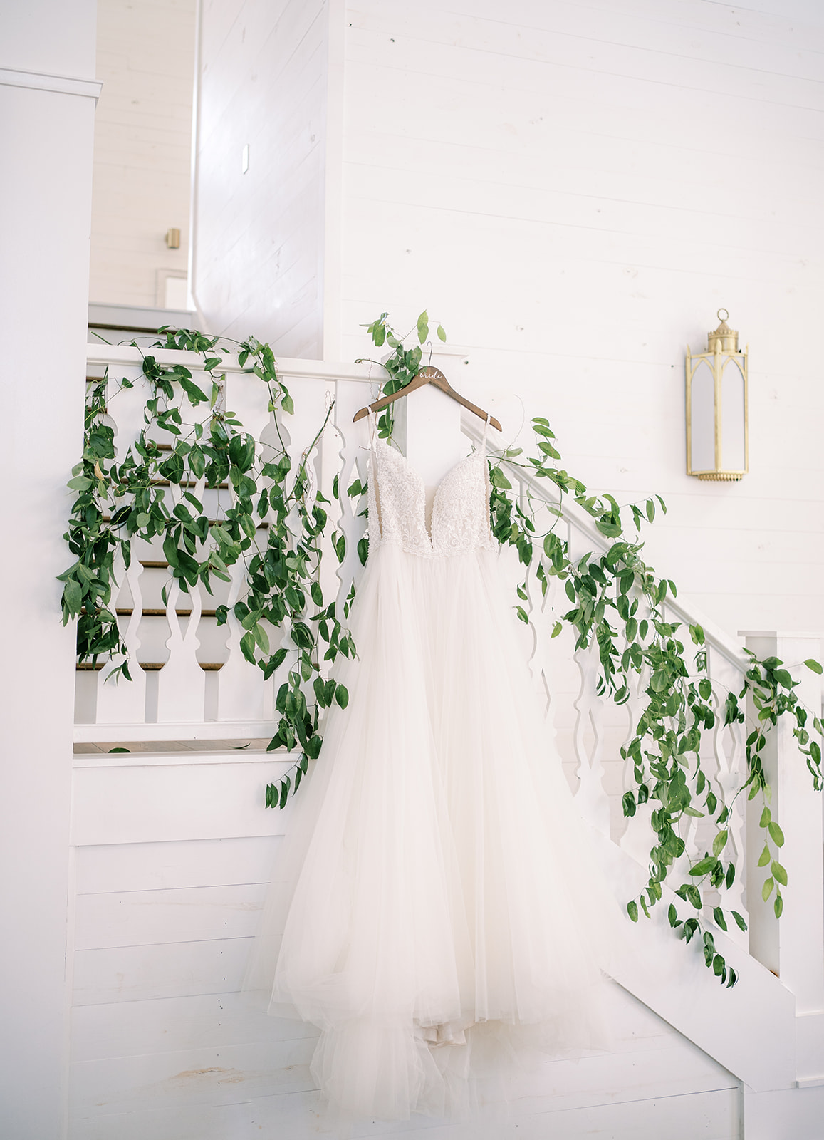 The bride's tulle a-line dress hangs on the banister at Harvest Hollow