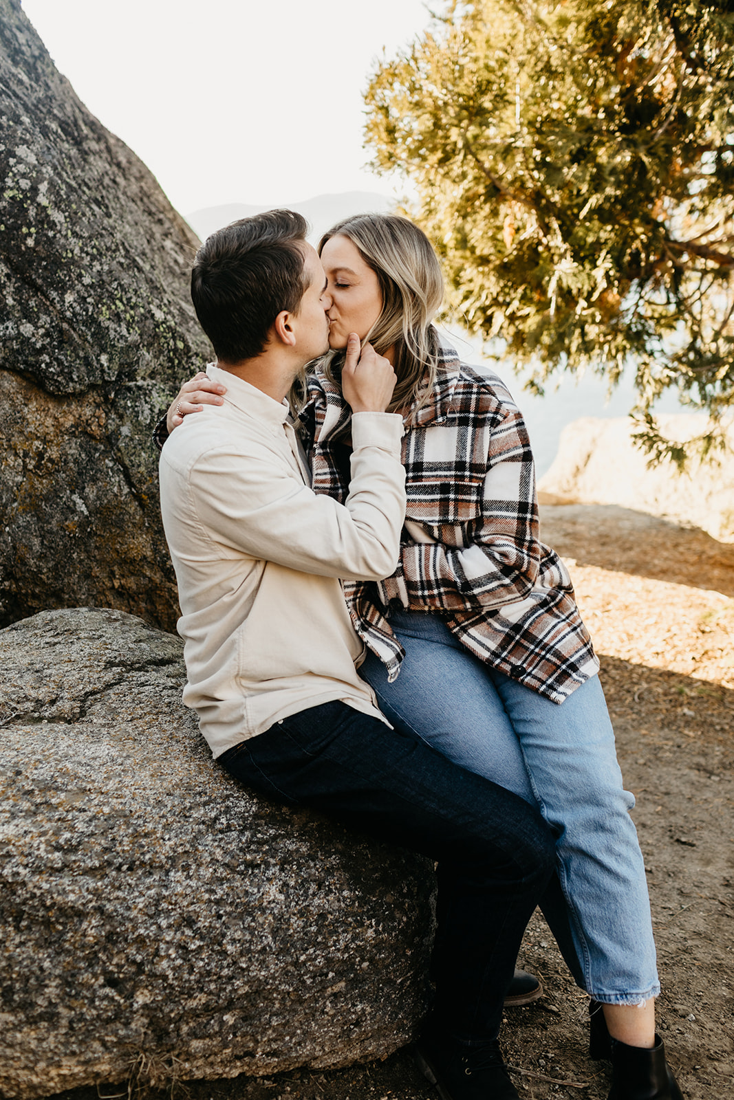 Couple sitting on rock in lake tahoe kiss 