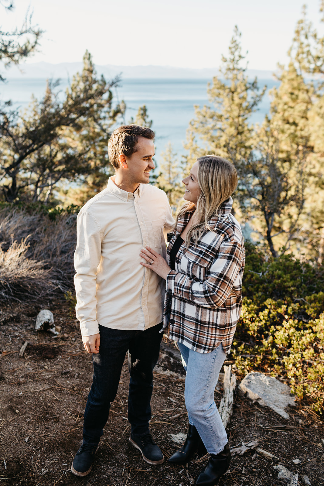 Couple wrapped up together with a view of Lake Tahoe in the back 