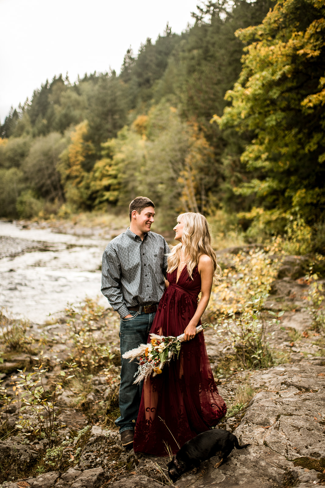 Oregon engaged couple embraces along the Molalla River with beautiful florals