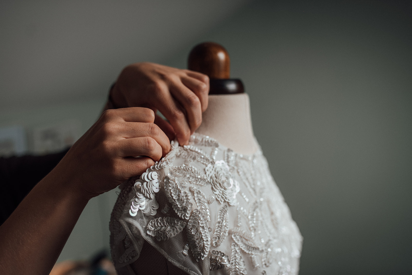 hands pinning a lace dress on a mannequin 