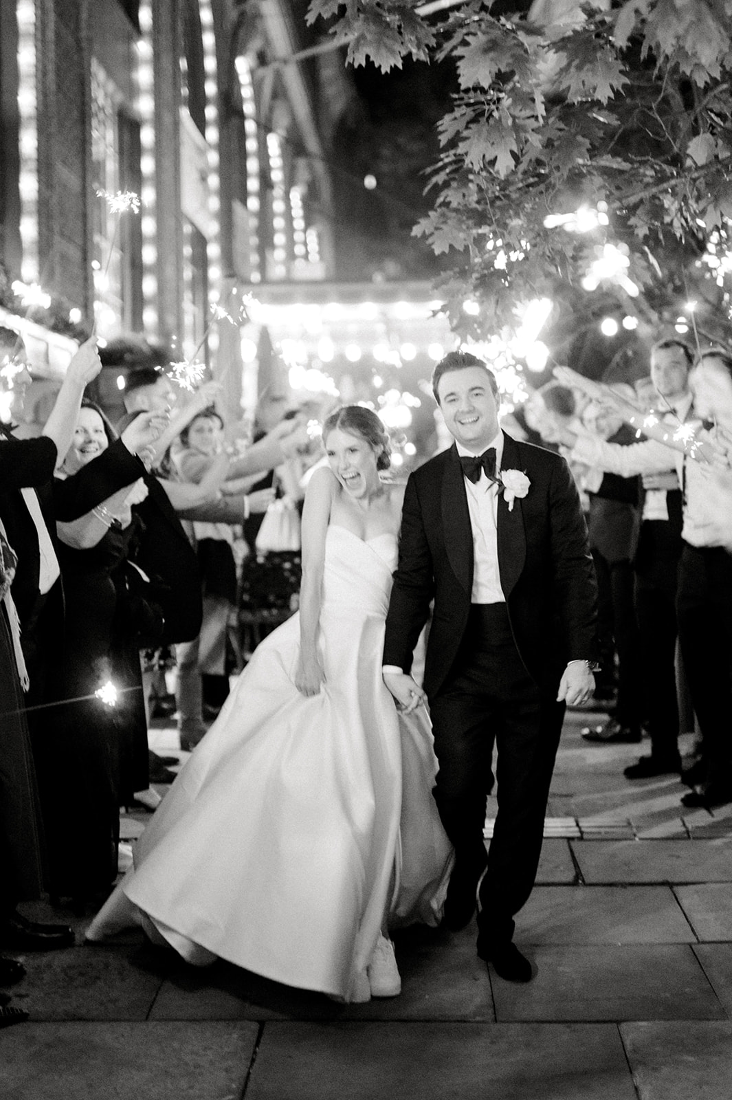 black and white photo of bride and groom exiting down aisle of sparklers