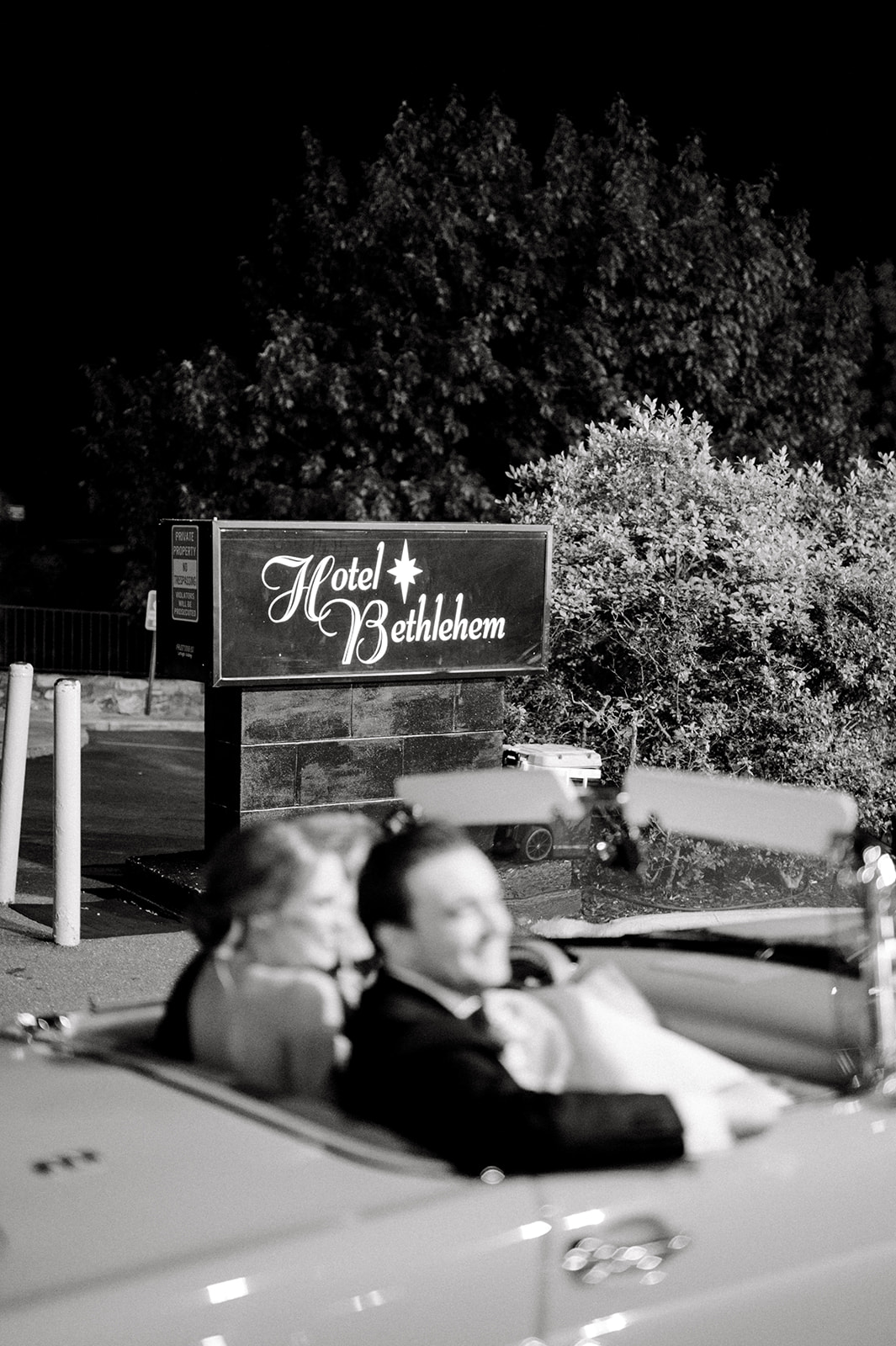 black and white photo of bride and groom in getaway car outside hotel bethlehem sign