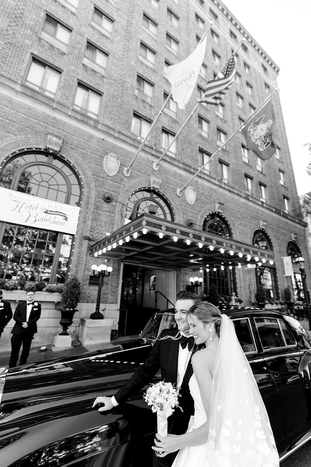 black and white photo of bride and groom with rolls royce outside hotel bethlehem