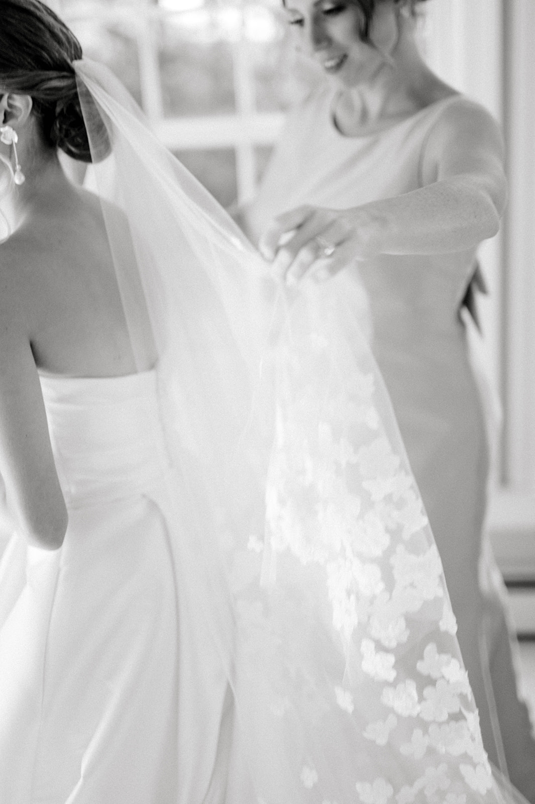 black and white photo of bride's veil being adjusted