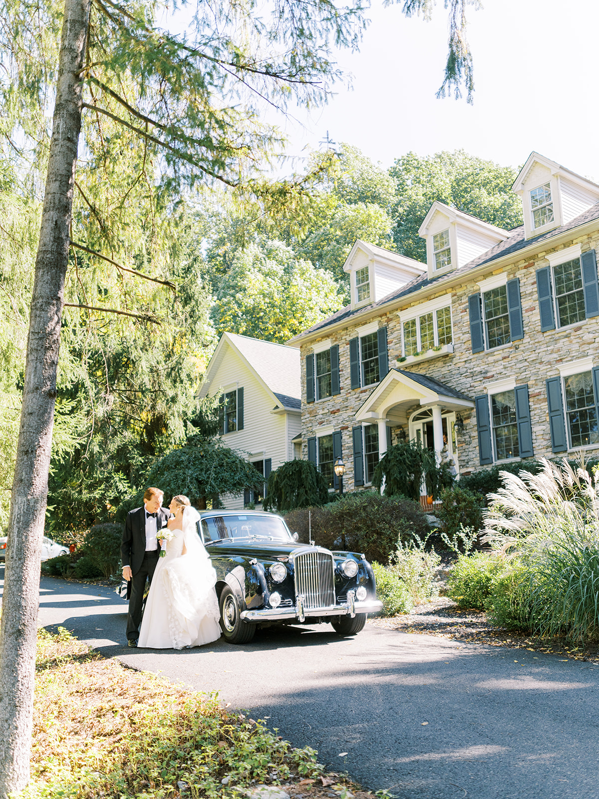 bride and father stand outside home with Rolls Royce