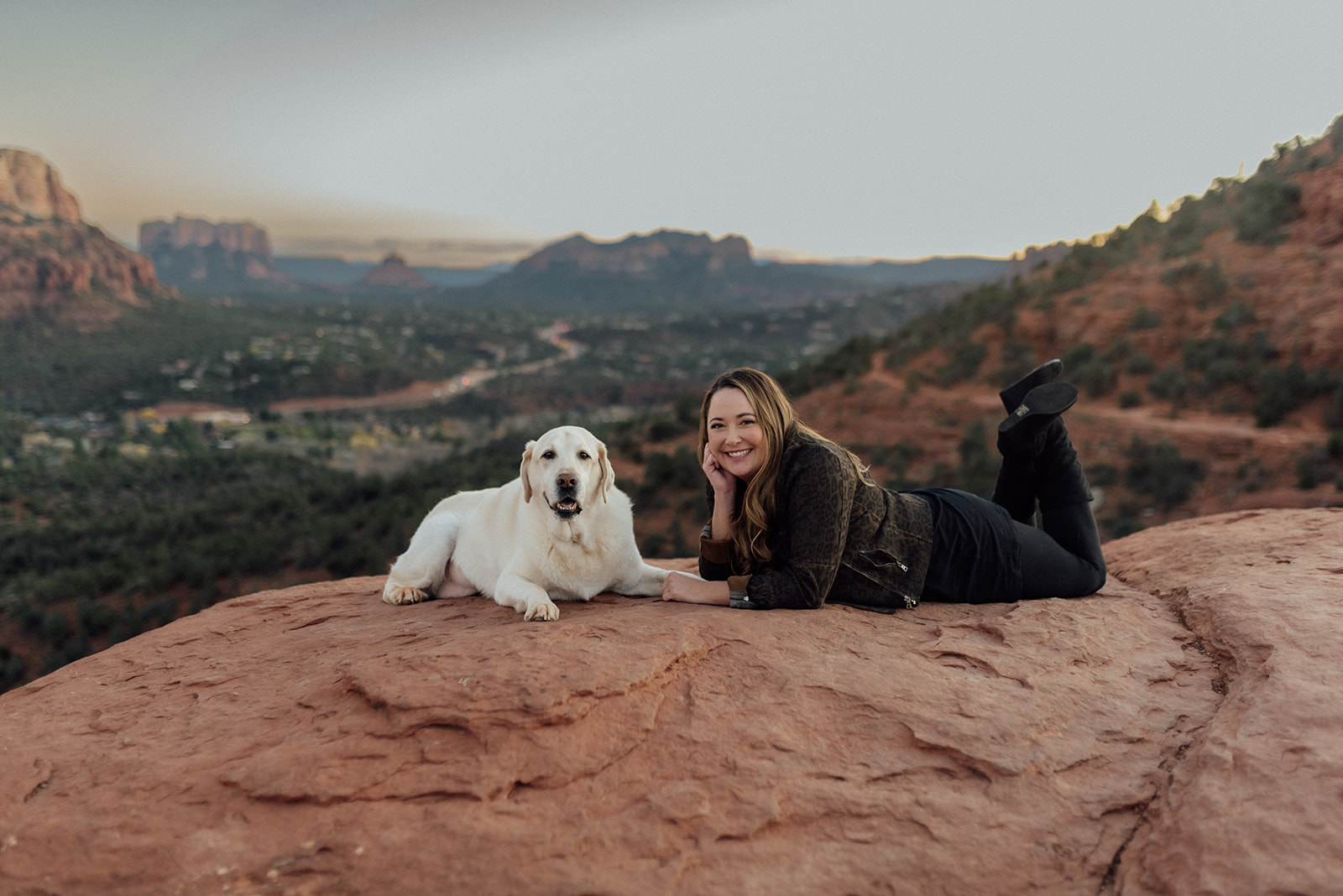 woman laying on a rock across from her dog in Sedona