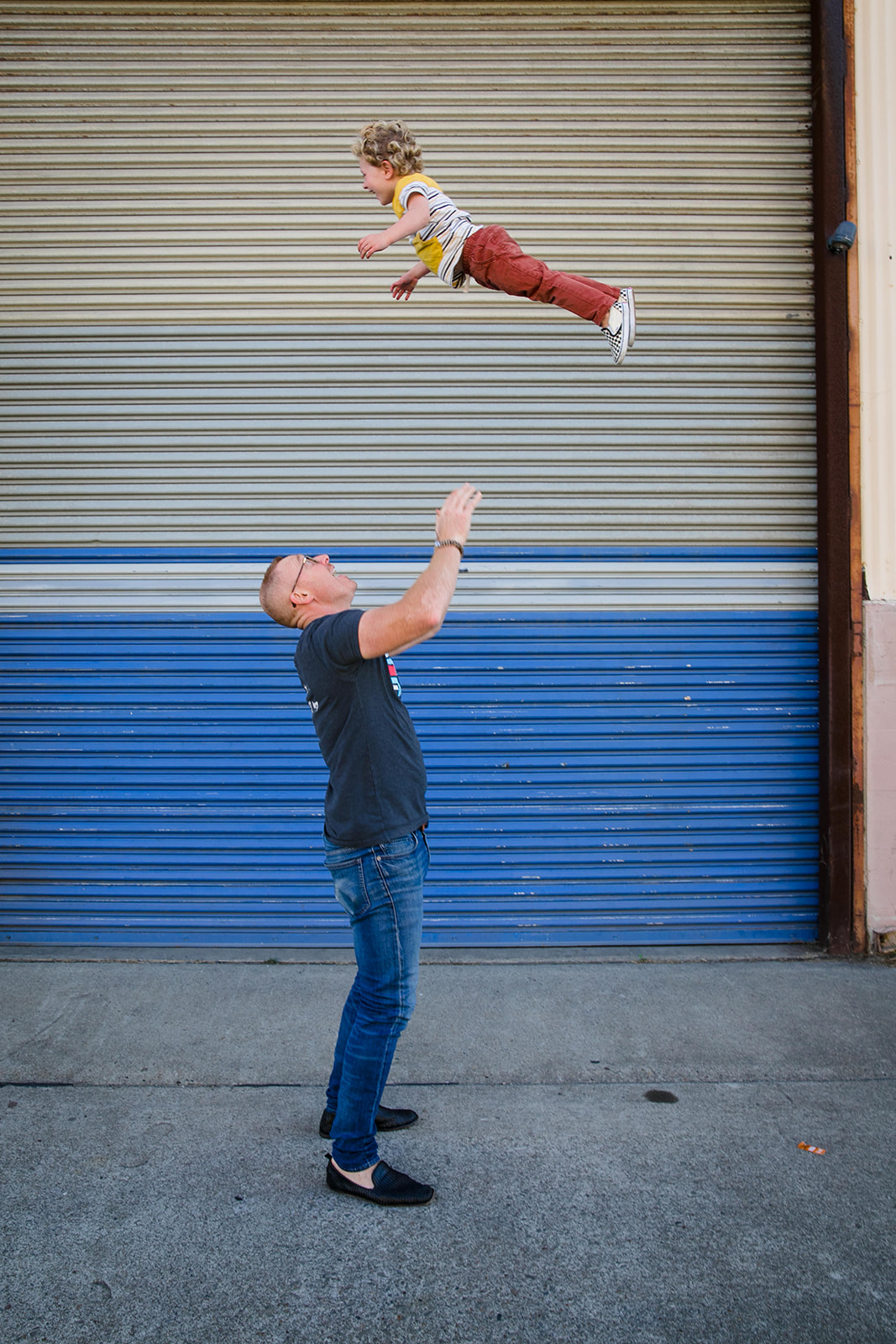 photo of father throwing toddler son in the air