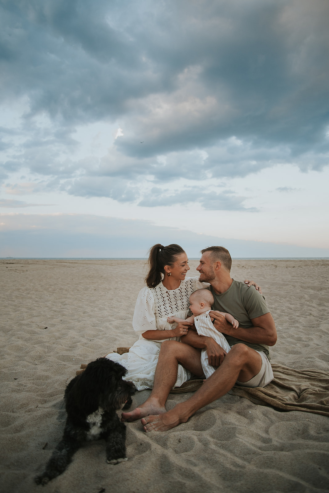 A family photoshoot at the beach with their 6 month old baby who is at the beach for the first time at sunset