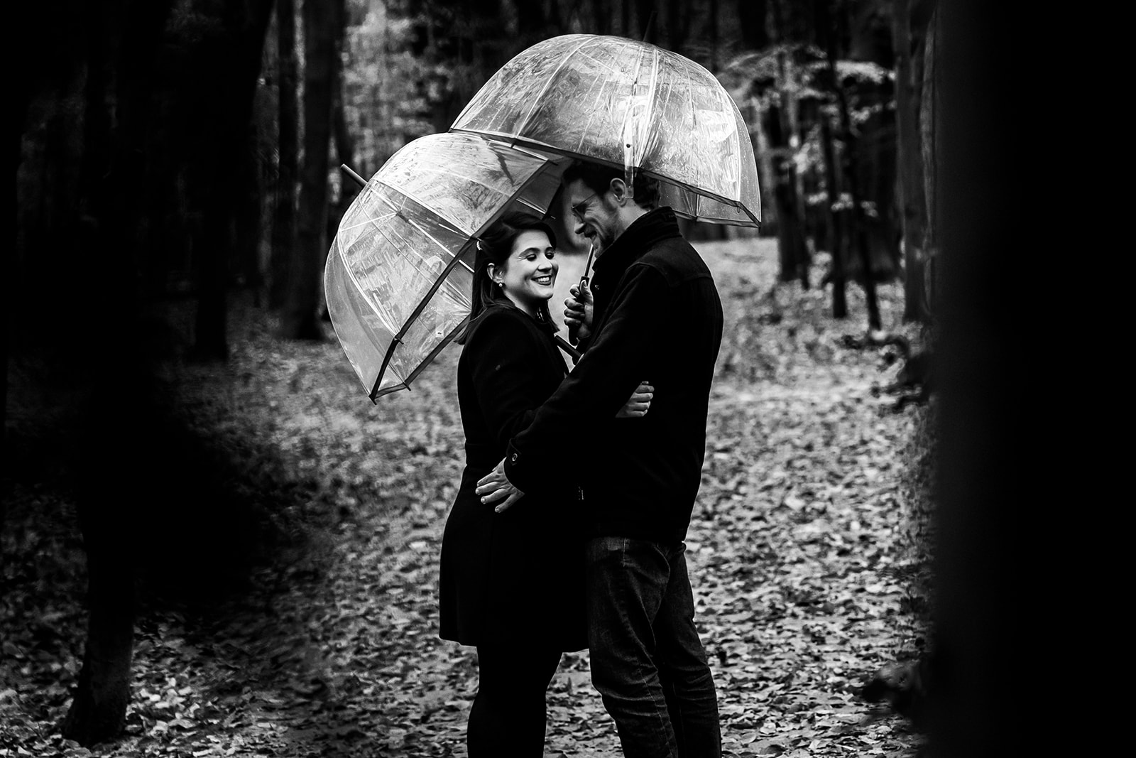 Un homme et une femme se tient sous deux parapluies transparents dans le bois de Bruxelles pendant un session photo 