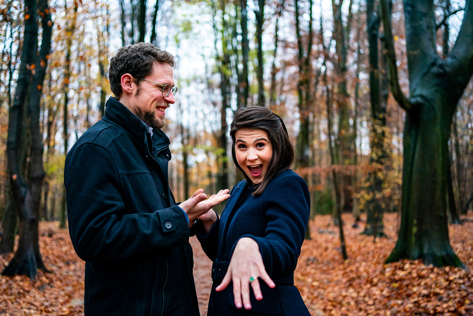Une dame montre sa bague de fiançailles d'un air excité à l'appareil photo au milieu des bois à Bruxelles 