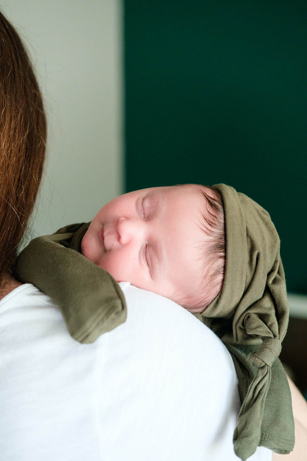 A newborn sleeps on his mom's shoulder during a Tampa newborn photography session shot at home in his nursery