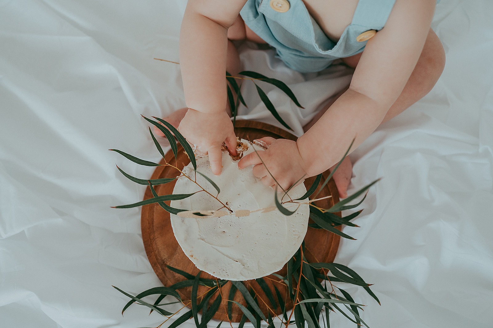 Baby smashing cake with eucalyptus leaves