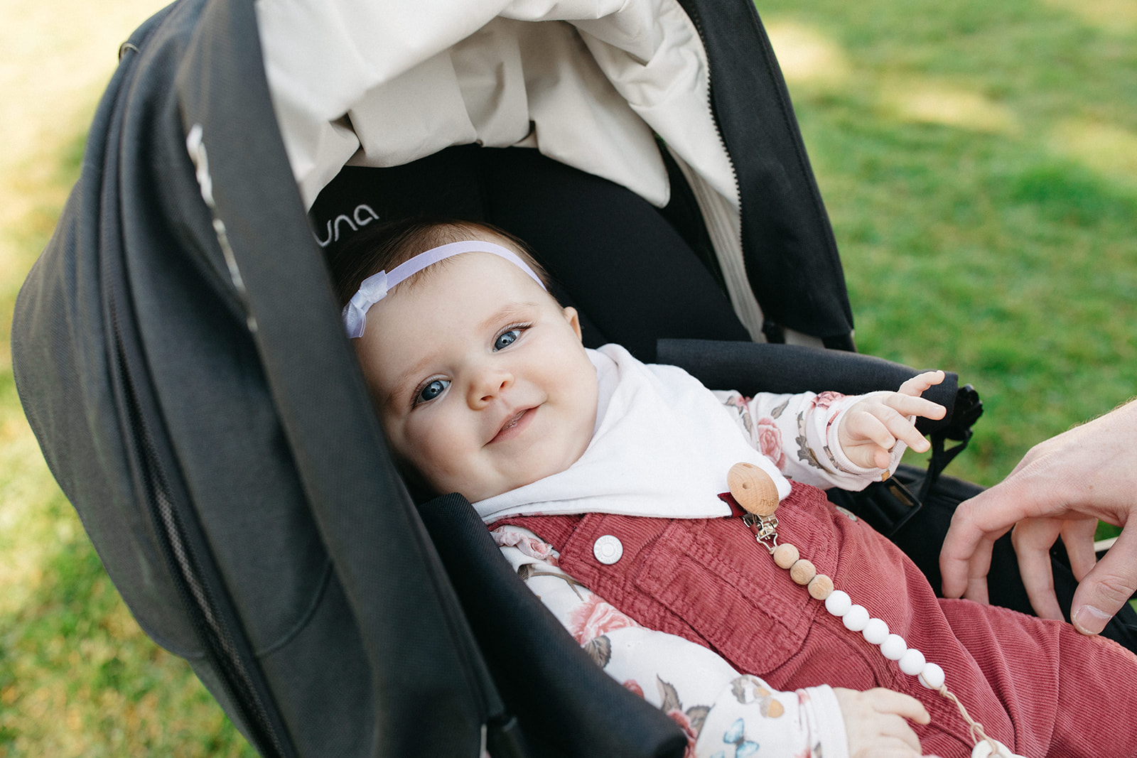 sweet baby girl in burgundy overalls sitting in stroller