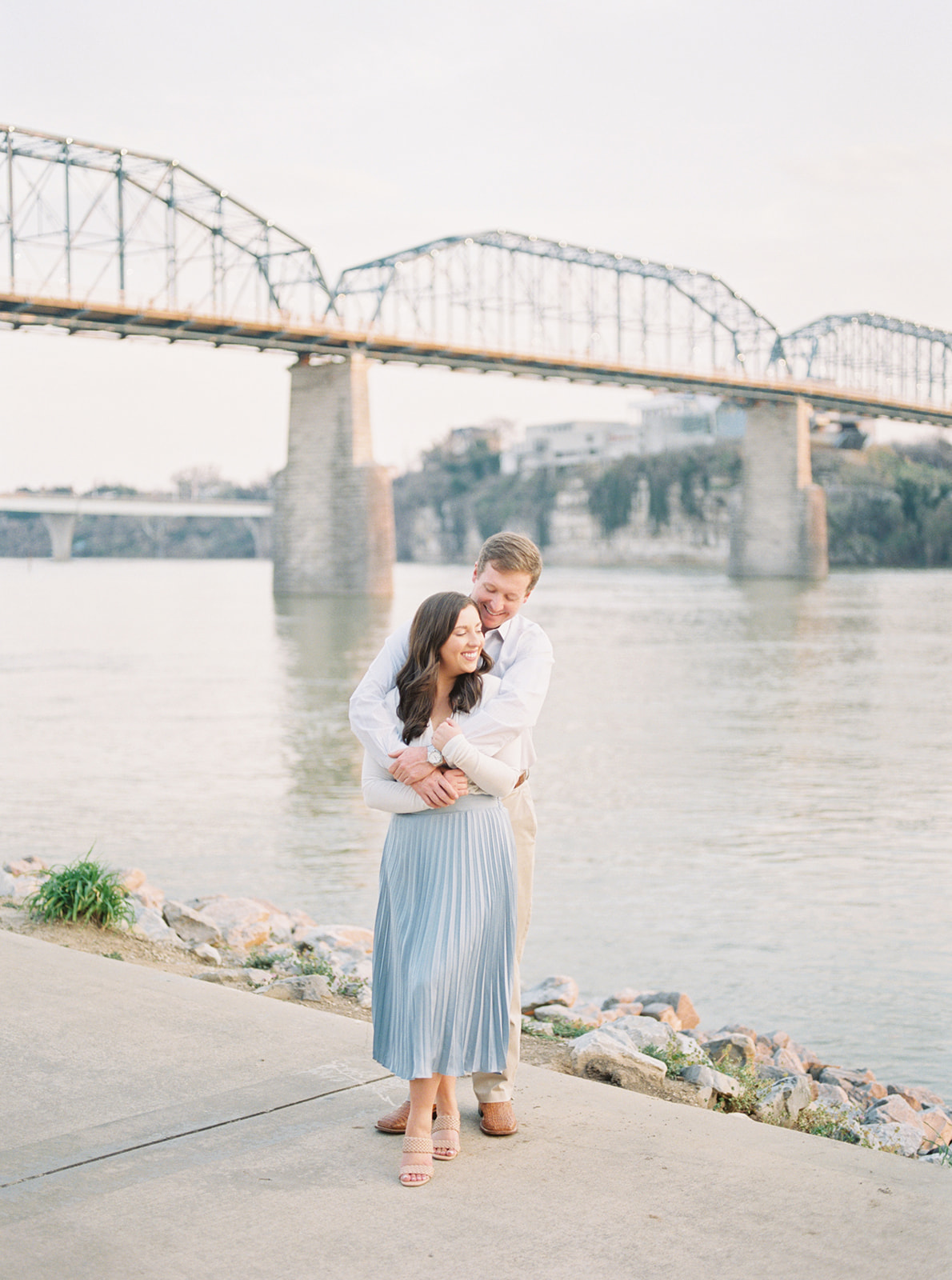 A couple embraces in front of the Walnut Street Bridge at Coolidge Park in Chattanooga, Tennessee