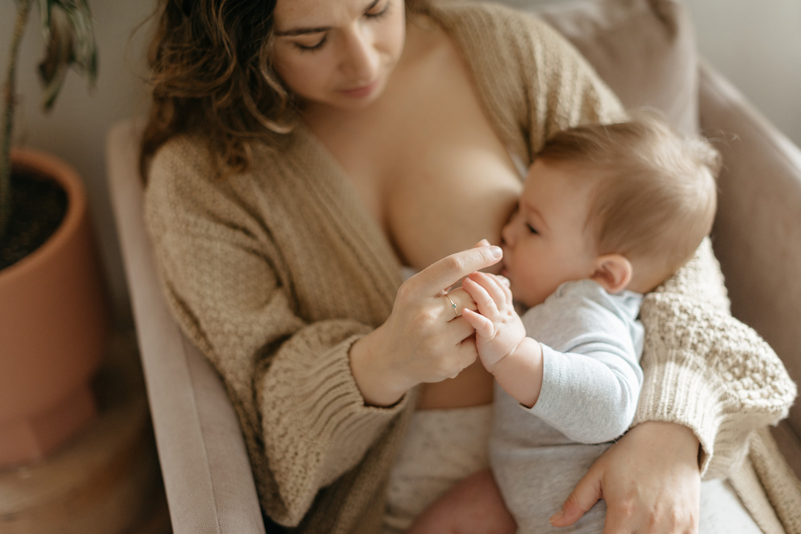 A mother and baby breastfeed on the couch in their home.