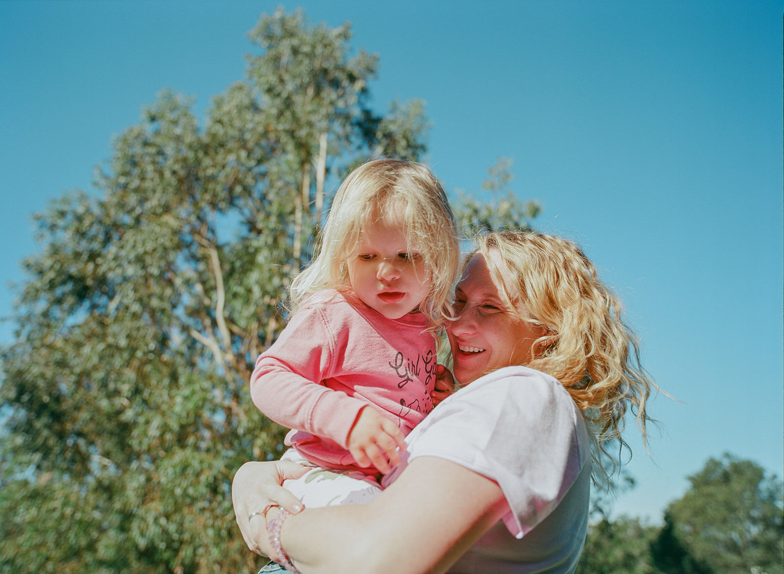 film photo of pregnant mom carrying toddler daughter in pink sweatshirt