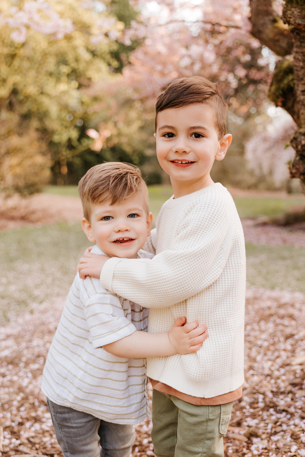 A close-up photo of young brothers hugging and smiling at the camera at a Seattle park.