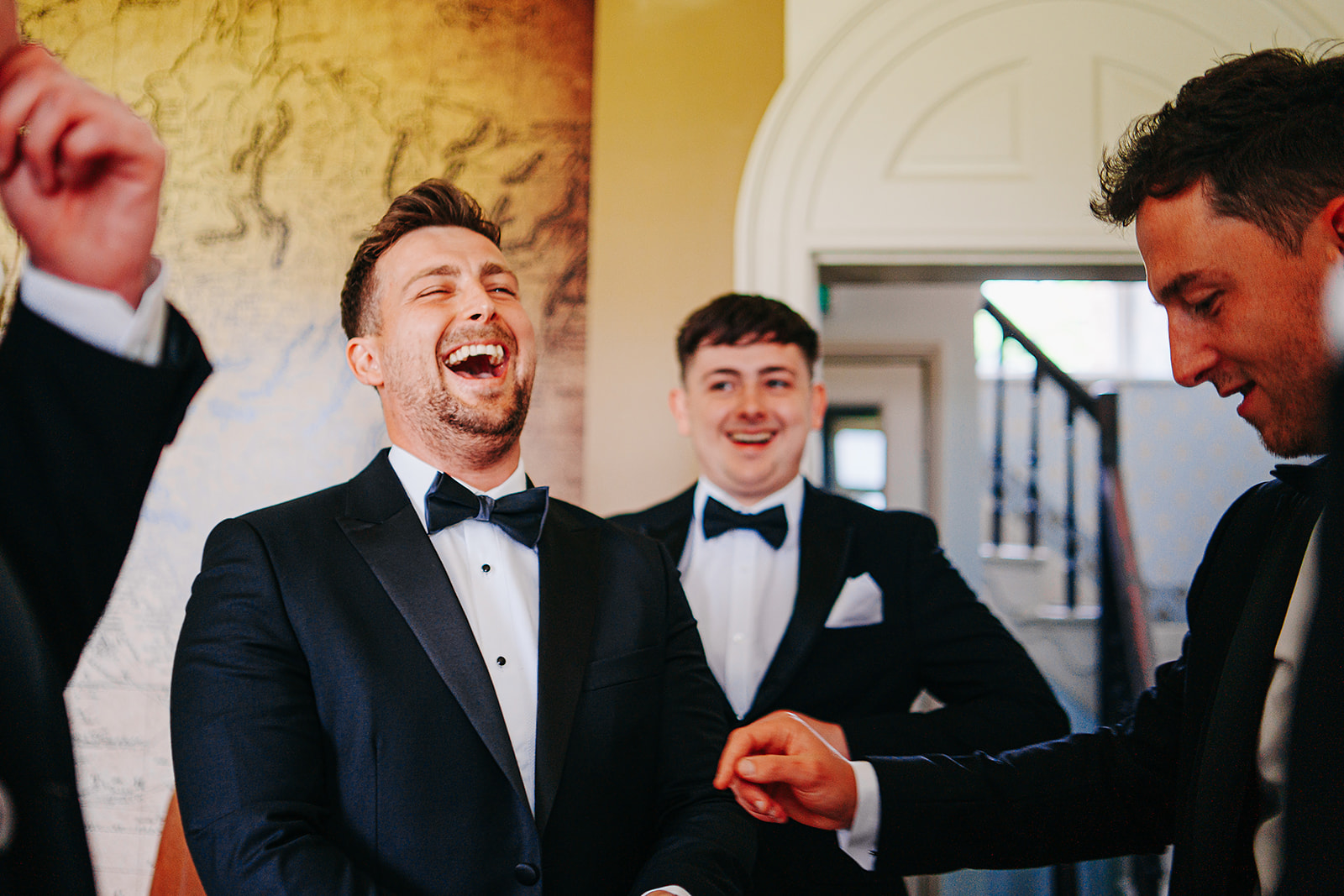 groomsmen in tuxedos laughing in the pool room of hornington manor 