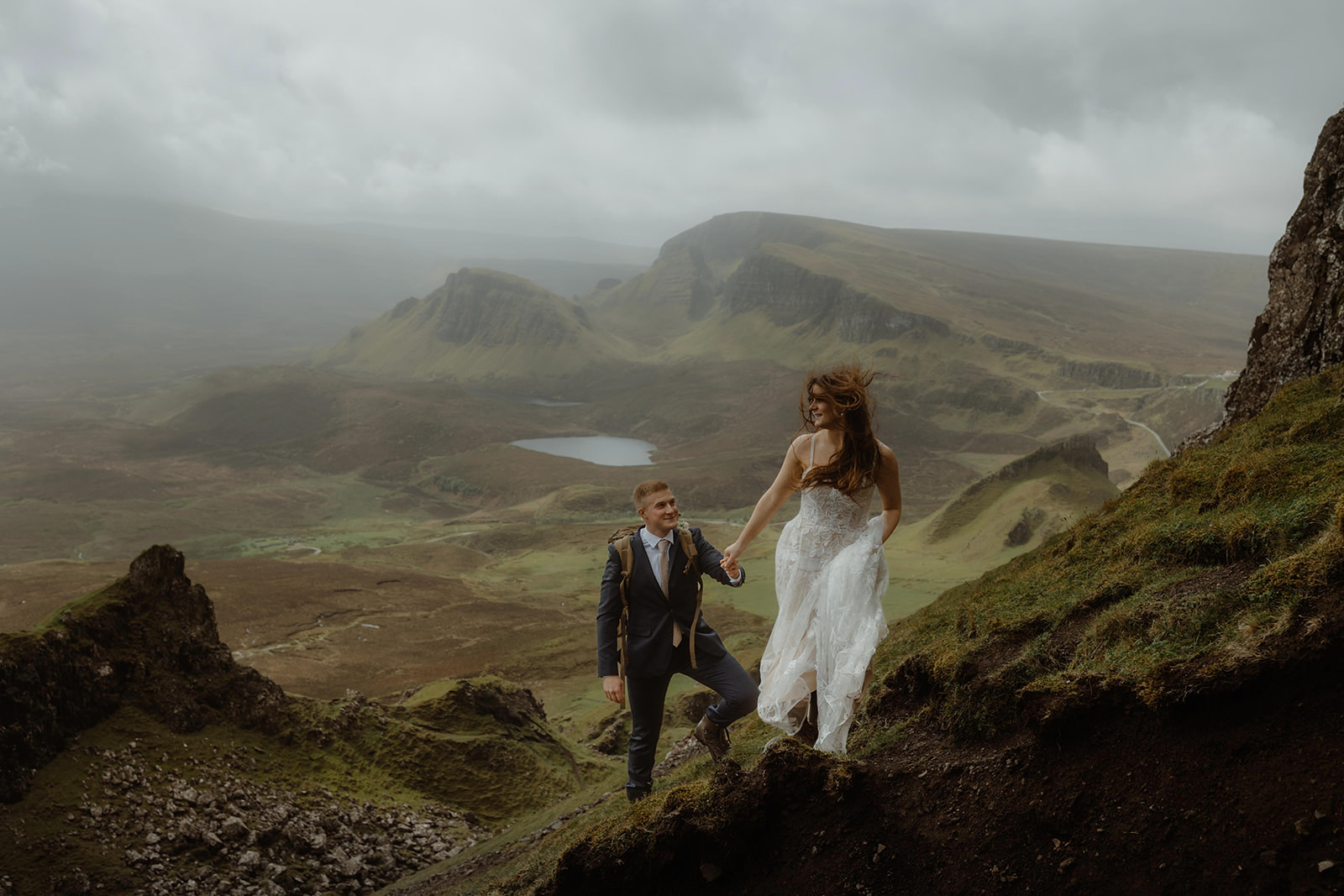 Elopement couples Emma and Matthew pose for a photo at Quiraing, Isle of Skye, with mountains in the background.