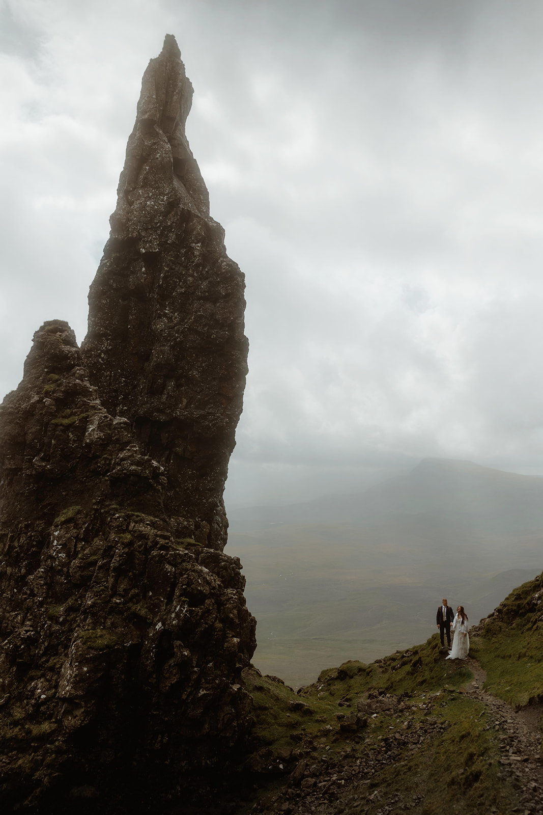 Elopement couple, Emma and Matthew walking hand in hand along the path next to the Needle at the Quiraing, Isle of Skye