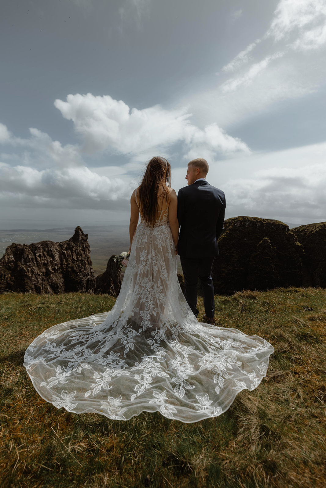 Emma and Matthew stand hand in hand as they admire the picturesque beauty of the Isle of Skye during their elopement day