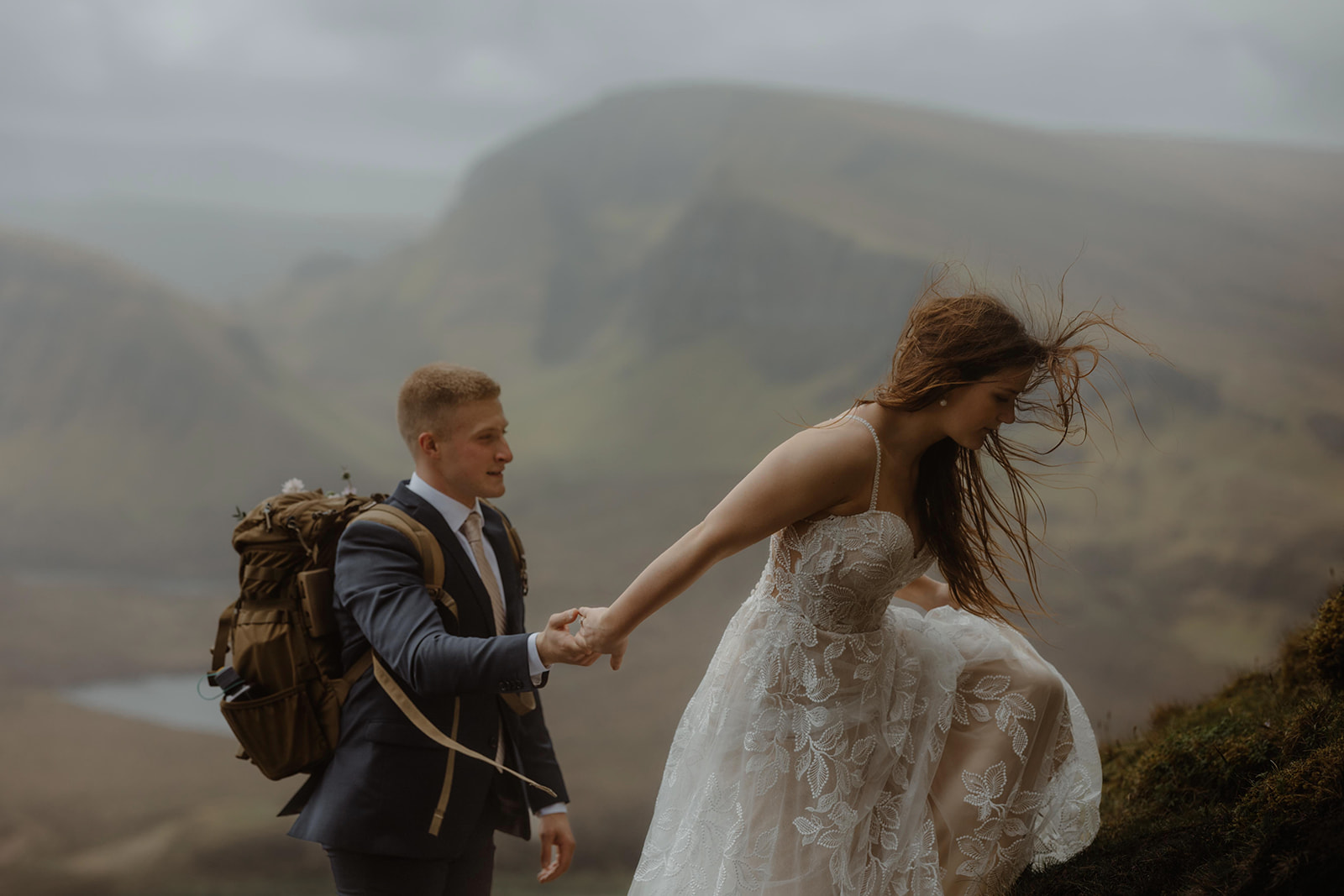 Emma and Matthew walking hand in hand on the Isle of Skye, with the misty mountains as their background
