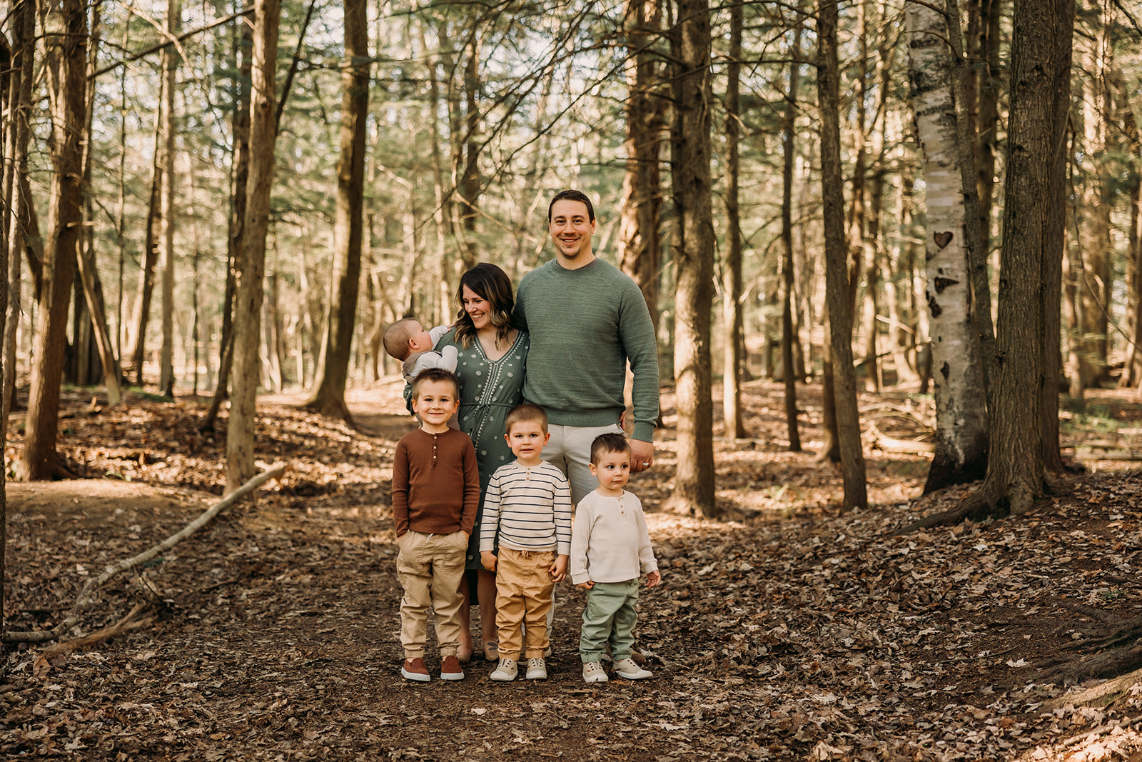 Smiling family in a forest photoshoot surrounded by lush greenery