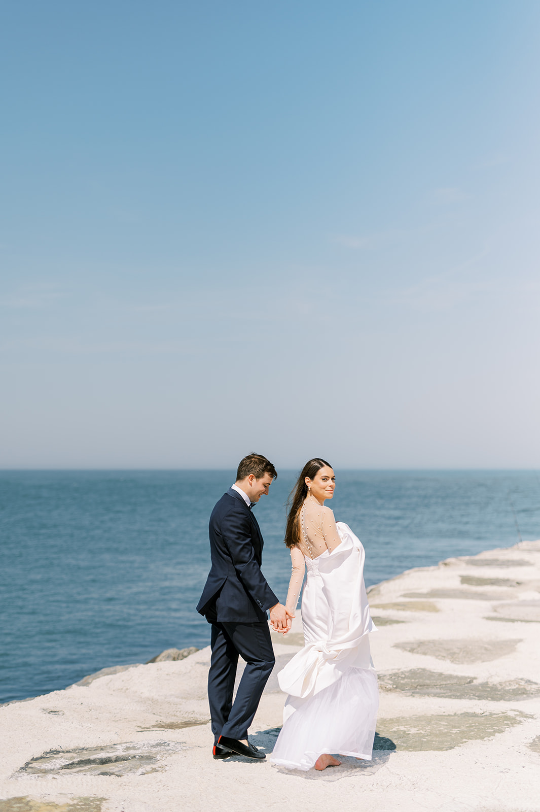 bride and groom walk into the blue sea abyss for Bright Summer Stone Harbor Golf Club Wedding in Yellow and Blue