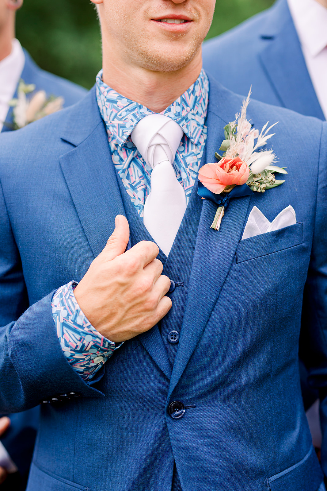 Groom style in blue suit featuring tie and boutonniere