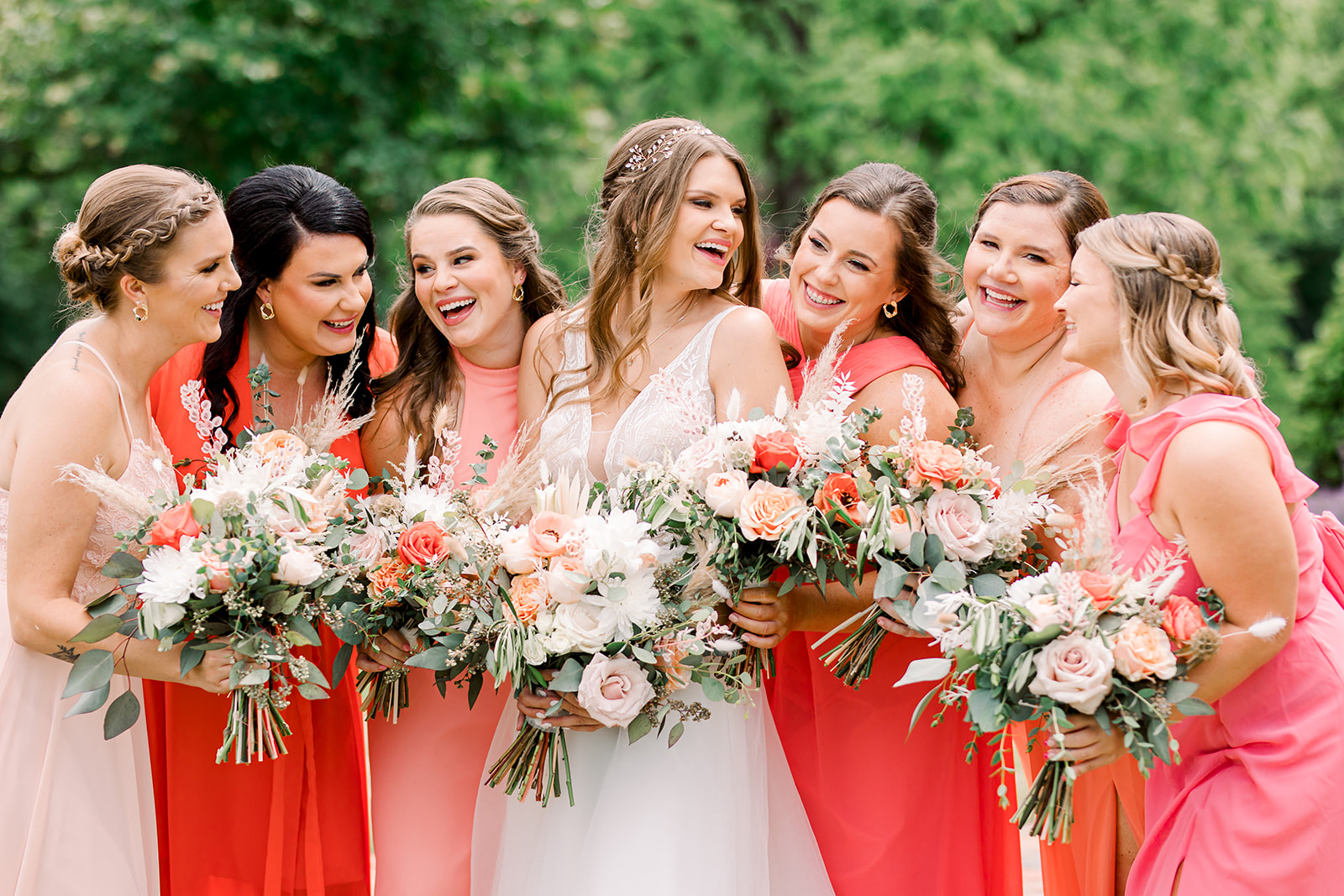 Laughing bride with bridesmaids in colorful dresses with wedding bouquets
